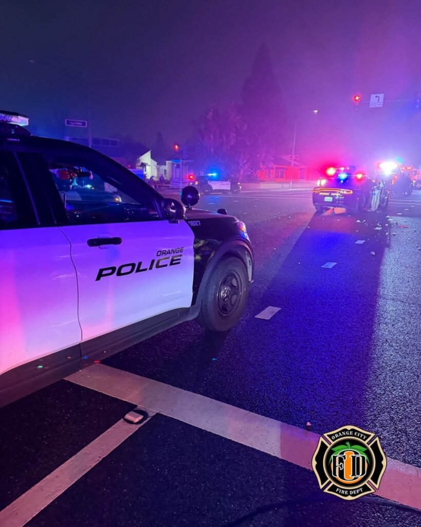 Multiple emergency vehicles with flashing lights at nighttime crash scene in Orange, including police and fire crews.