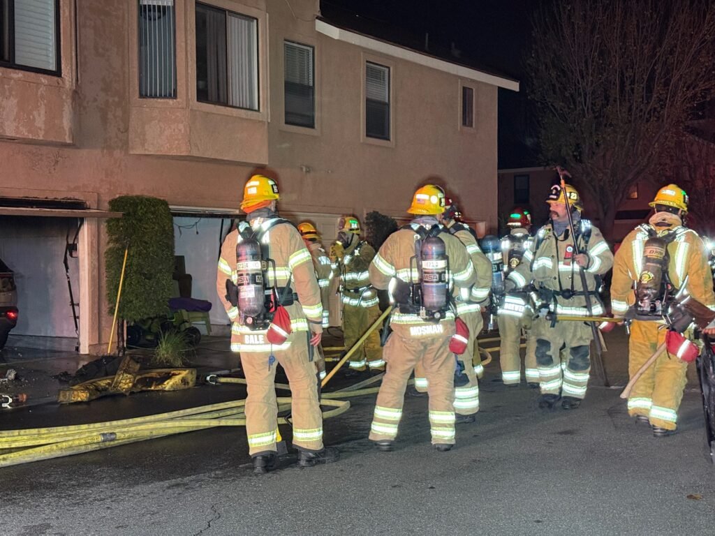 Firefighters in full gear standing near the garage area after extinguishing the fire at the Orange condo complex.