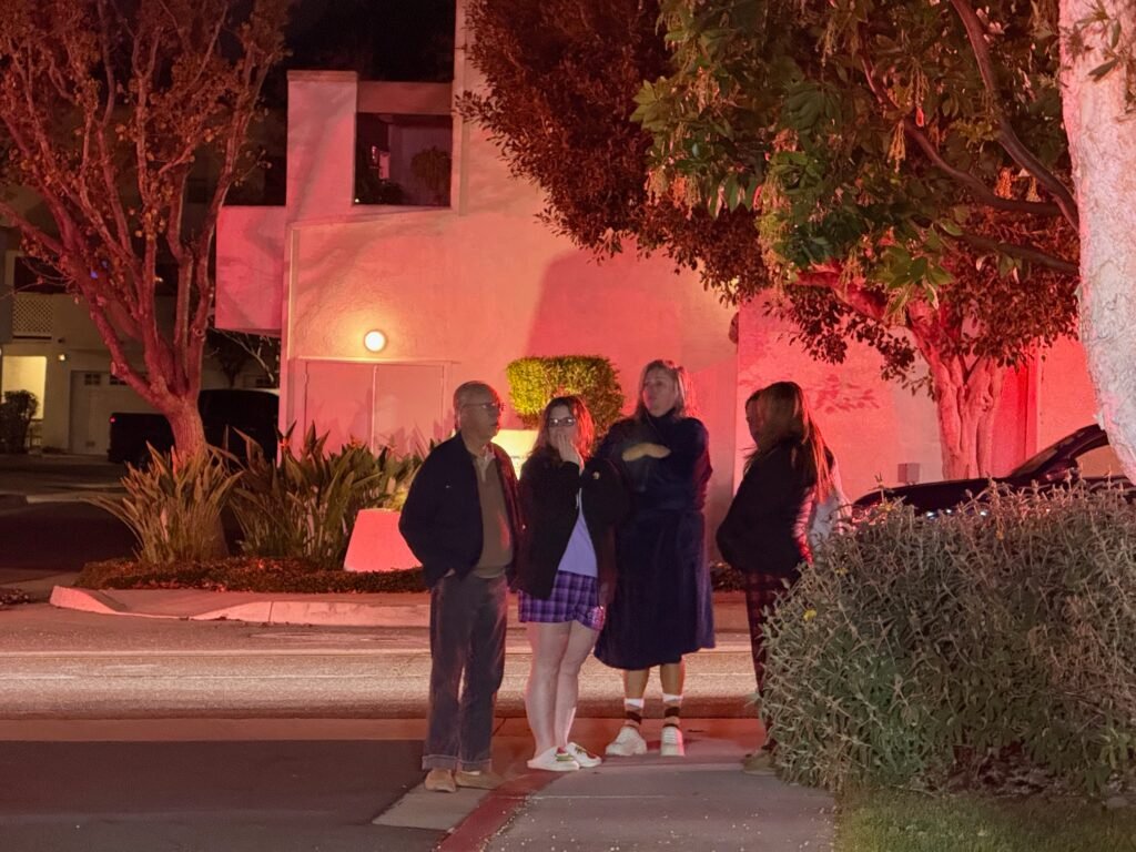 Residents gathered outside the condo complex illuminated by red emergency lights during the fire response.