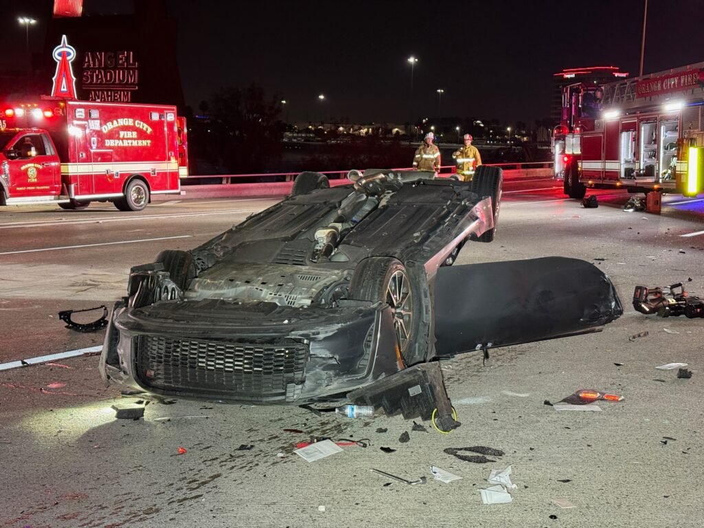 Severely damaged car resting on its roof amid freeway debris