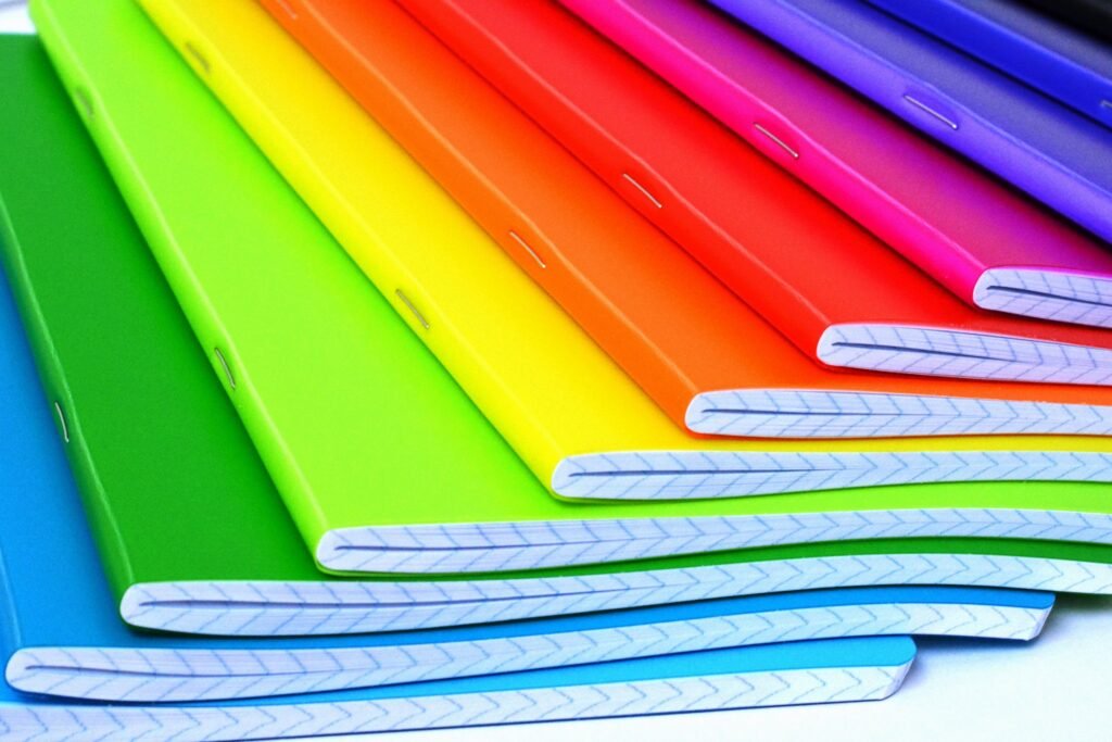 Colorful exercise notebooks arranged in overlapping rows.